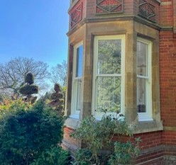 Bay window with white timber sash windows set in stone mullions on a Victorian brick property